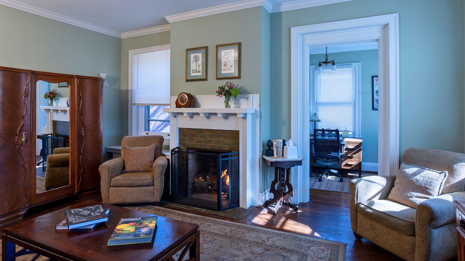 A cozy living room featuring a fireplace, comfortable seating, and a workspace.