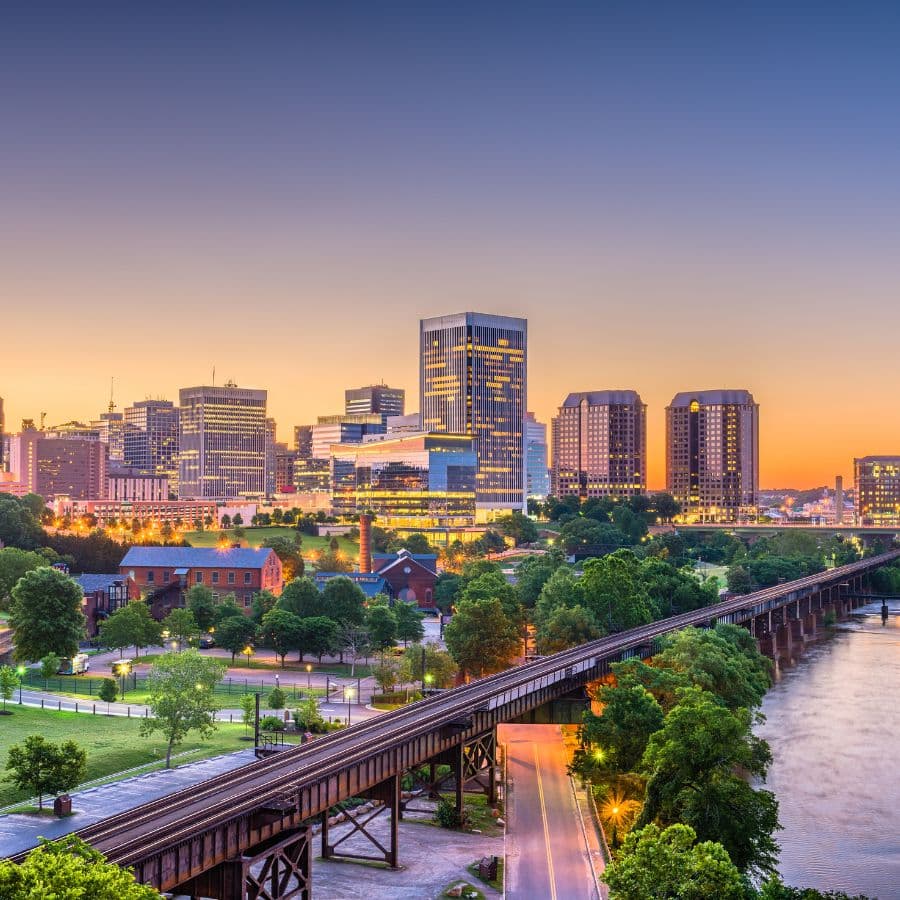 A vibrant city skyline at dusk with buildings, trees, and a river.